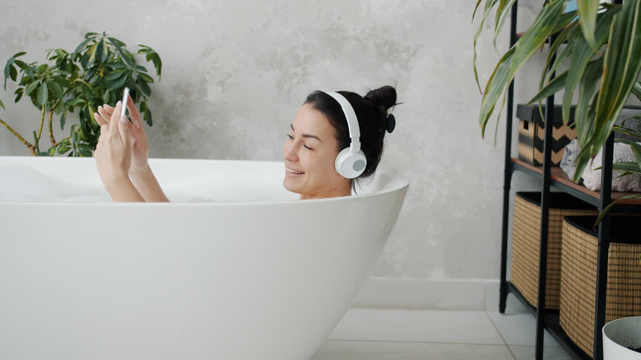 Woman Relaxing in Bathtub with Headphones and Smartphone