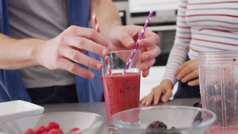 Video-of-midsection-of-diverse-couple-putting-straws-into-glass-with-juice