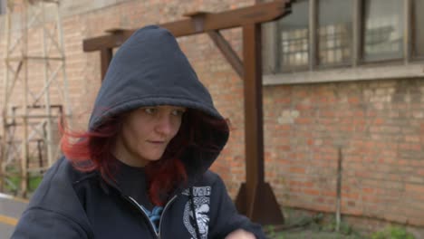 mysterious girl in a hoodie walking through an industrial place