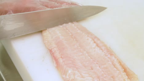 chef cutting raw white fish, close-up