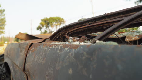 Vista-De-Cerca-De-Un-Vehículo-De-Automóvil-Abandonado-Oxidado-Que-Se-Estrelló-Inútilmente-De-Un-Incendio-Forestal-En-El-Paraíso,-CA