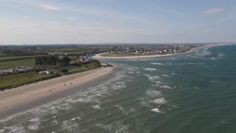 toma de drone de una playa soleada y una pequeña ciudad costera en irlanda