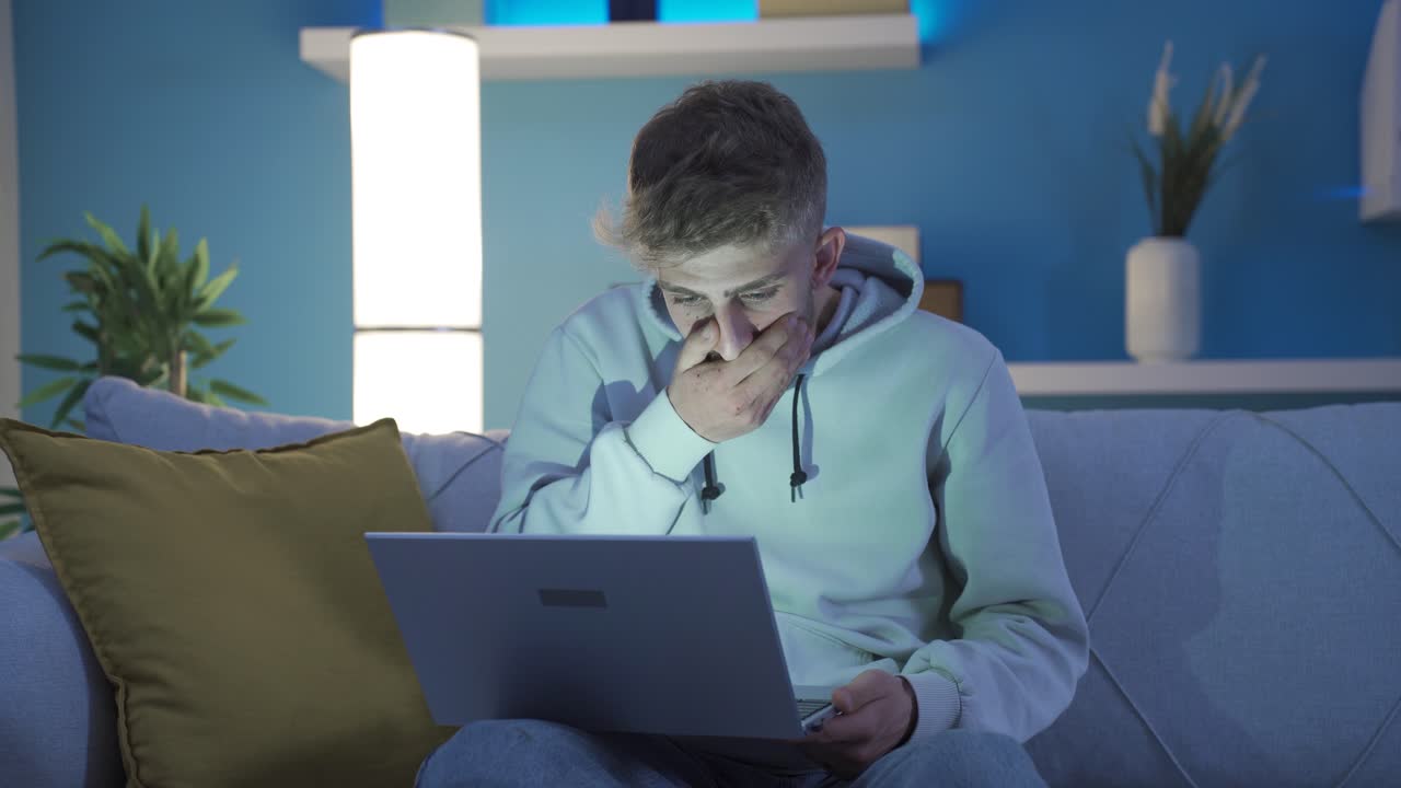 mientras el joven está usando una computadora portátil en casa, está frustrado con las noticias que recibe con sorpresa.