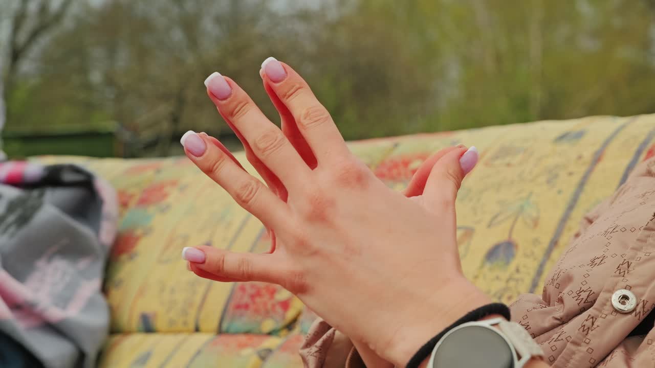 Mano femminile delicata con manicure pallida appoggiata all'aperto in primavera, slow motion