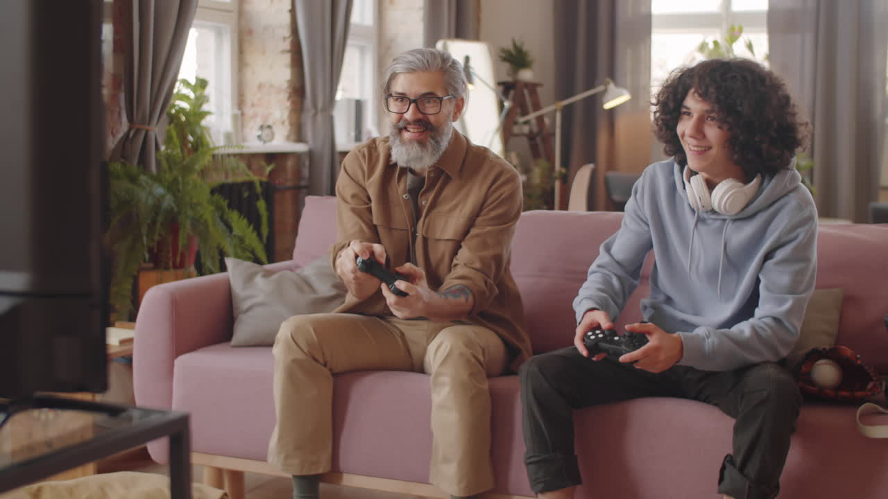 즐거운 아버지와 아들이 함께 콘솔 게임을 하고 있습니다.