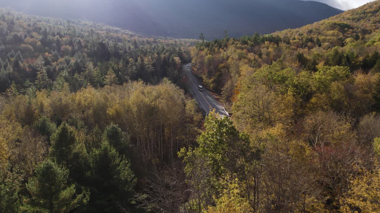 버스 가 가을 에 미국 메인 주 그래프턴 노치 주립 공원 에서 숲 한가운데 로 운전 하고 있다