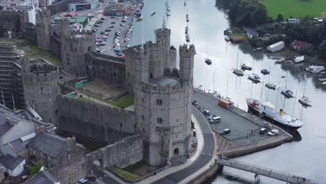 ancient caernarfon castle welsh harbour town aerial view medieval waterfront landmark birdseye close orbit right