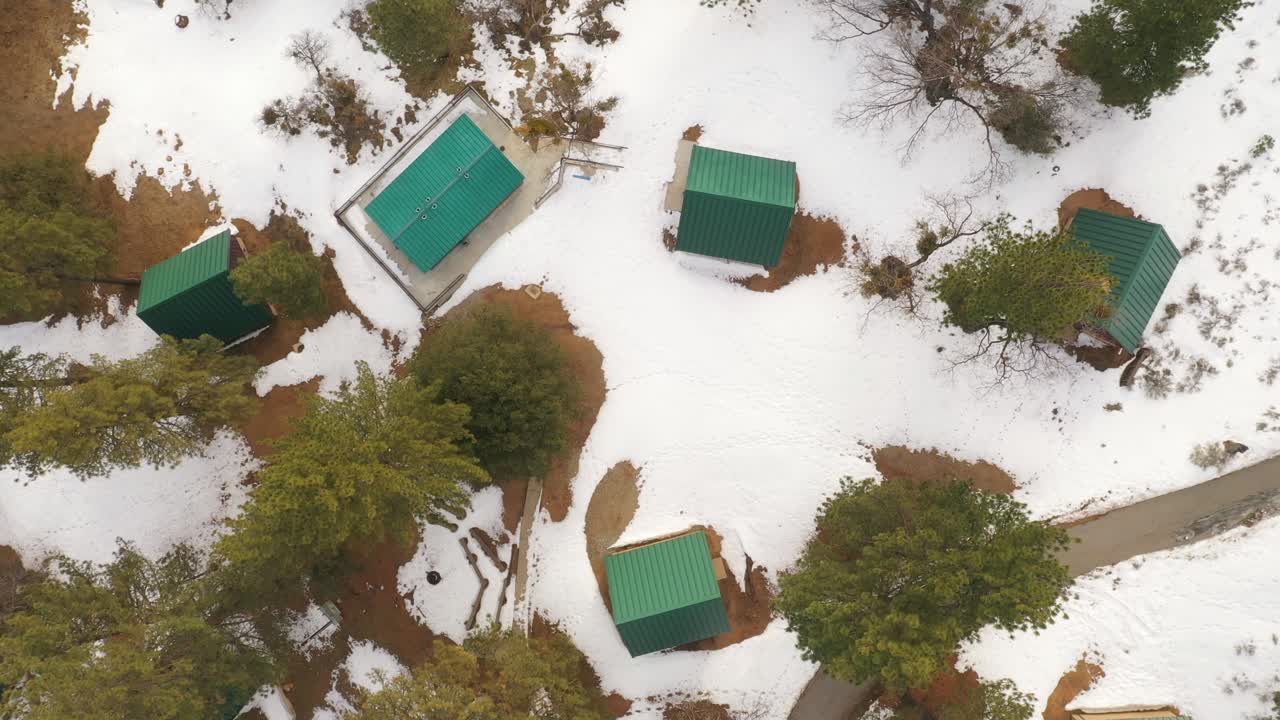 las cabañas con armazón en las montañas nevadas brindan calor y refugio del invierno: vista aérea directa hacia abajo