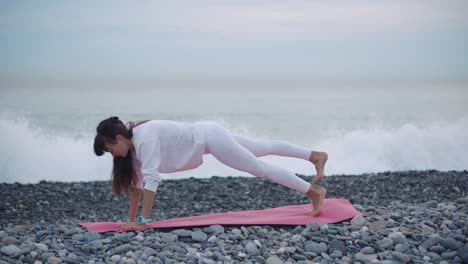 mujer practicando la postura de tabla en una playa
