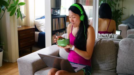mujer usando una computadora portátil mientras desayuna