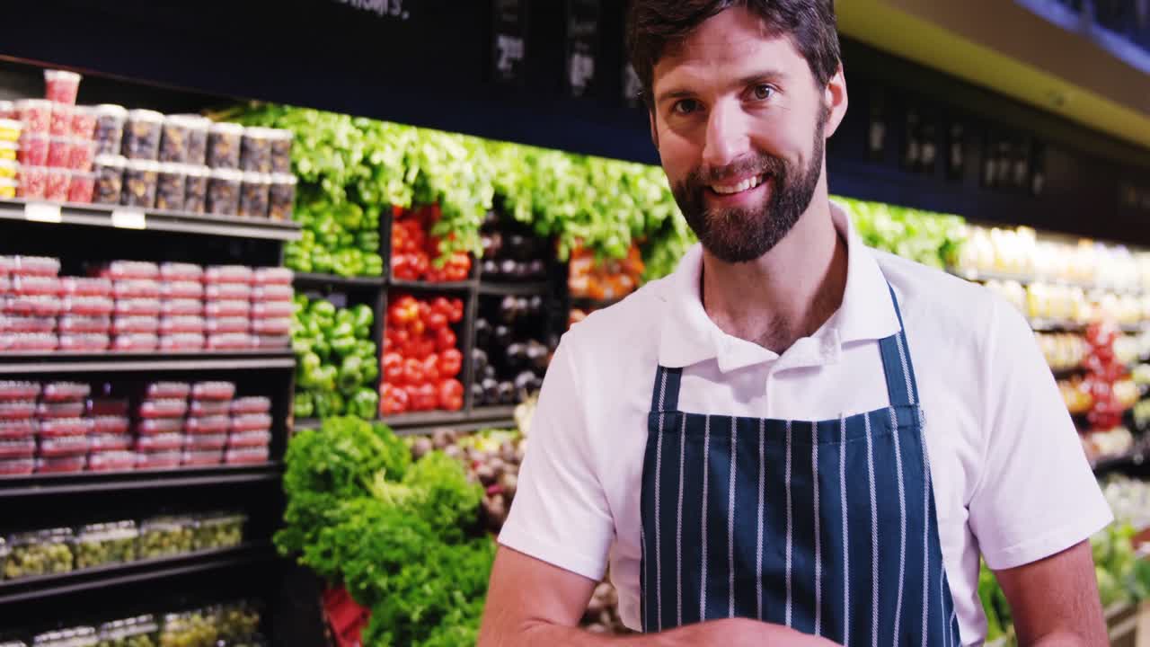 personal masculino sonriente sosteniendo frutas en la sección orgánica del supermercado