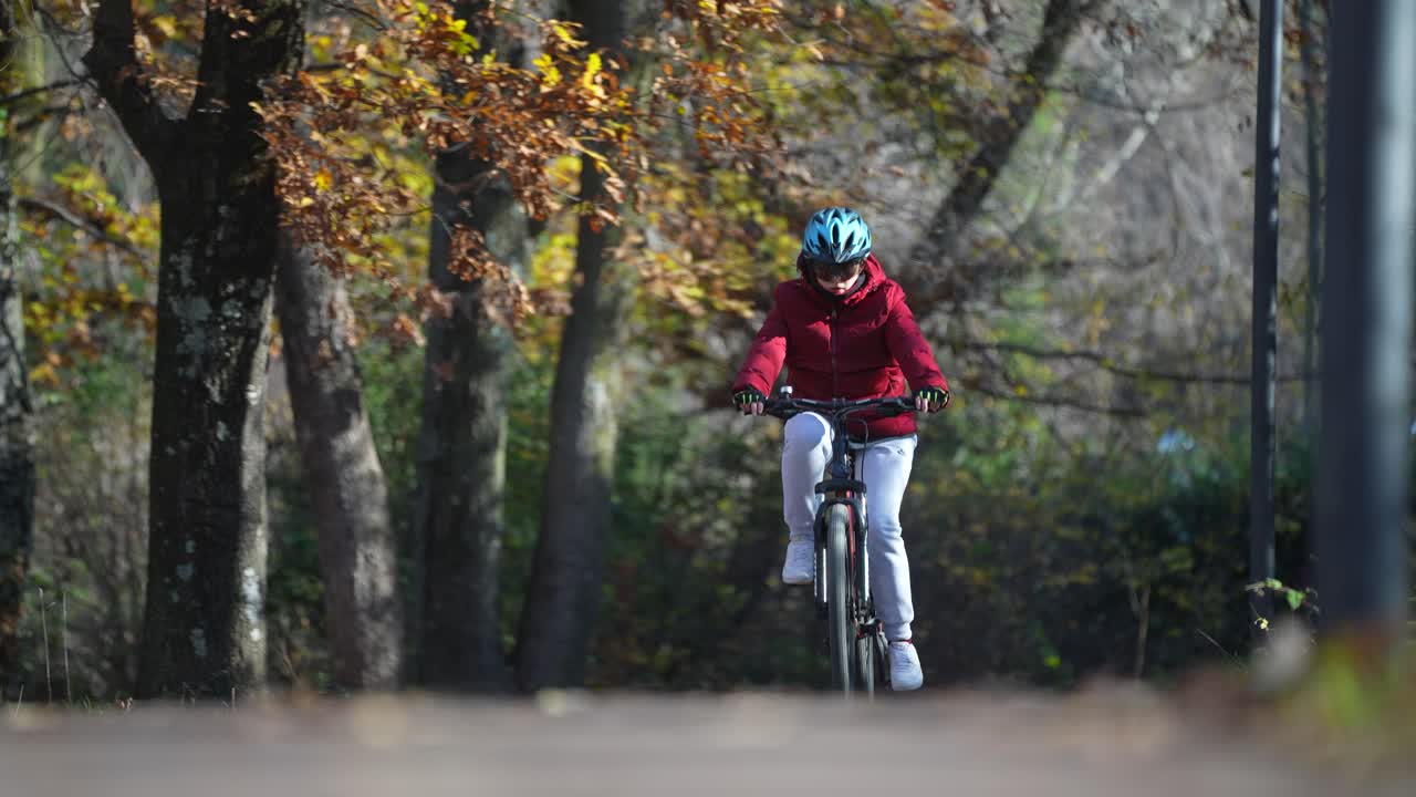 paseo en bicicleta a través de árboles del bosque, sendero del parque ciclismo con bicicleta de montaña chica con casco y gafas