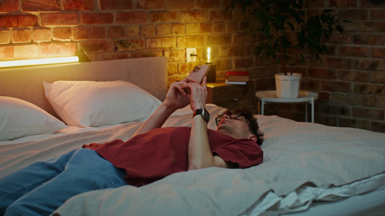 밤에 침대에서 스마트폰을 사용하는 남자
