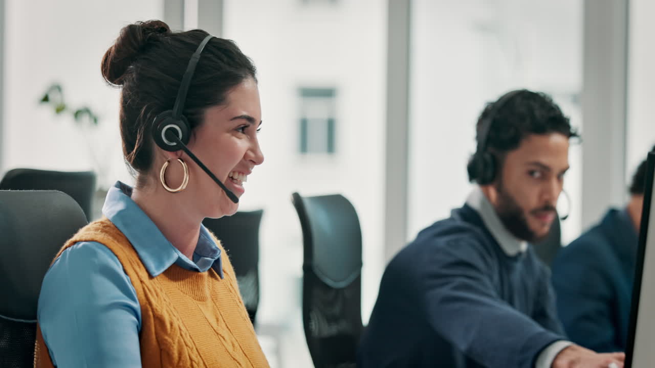 Smilende kvinne med headset arbeider på et travelt call center-kontor.