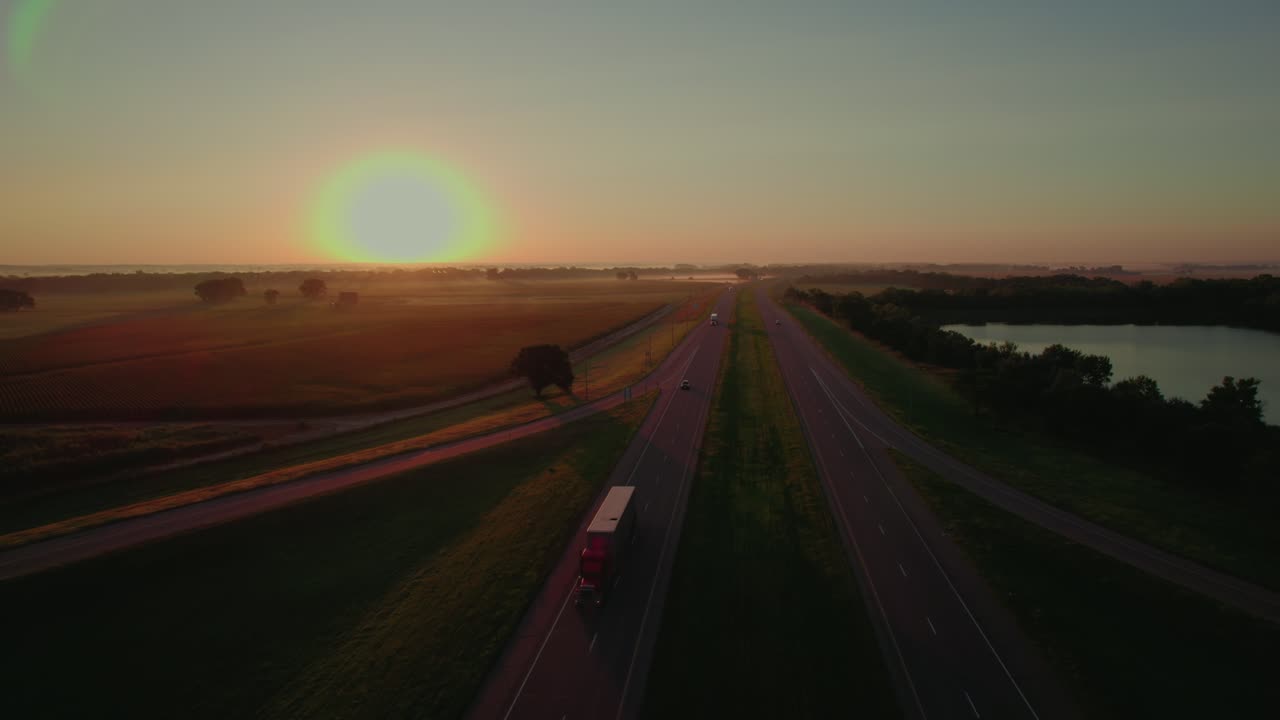 Ripresa aerea di un semirimorchio rosso che percorre la I-80 in Nebraska durante un'alba dorata