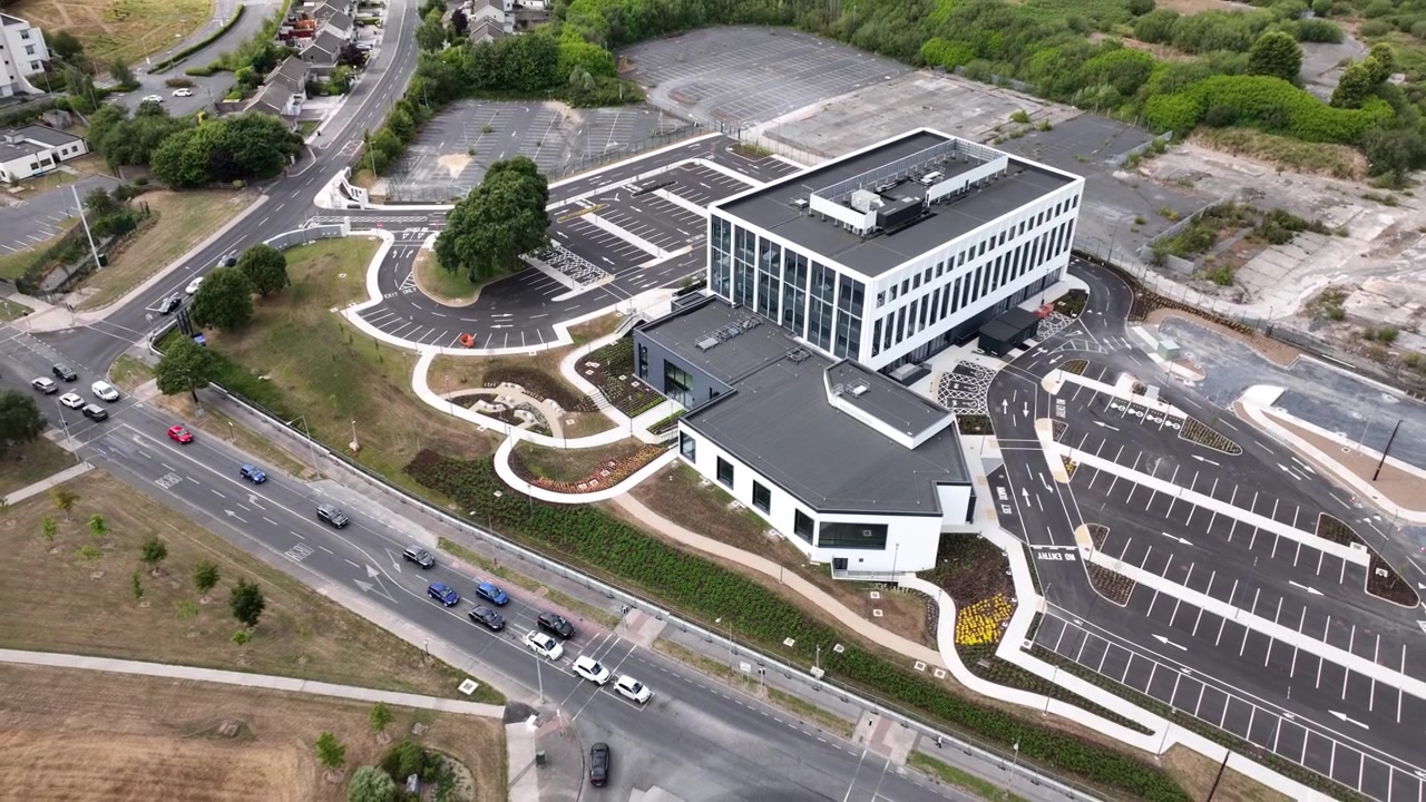 Perspectiva de drone zenital do New Glassworks Centre, destacando sua área de implantação, entradas, estradas circundantes, áreas de estacionamento e propriedades vizinhas. Adequado para apresentações corporativas.