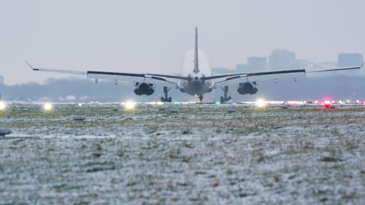 雪が積もった空港の滑走路に着陸する大型旅客機