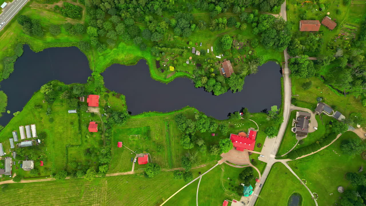 A Picturesque Landscape Showcasing a Lake Encircled by Lush Greenery and Trees, With Houses Scattered Throughout the Area - Aerial Topdown Shot