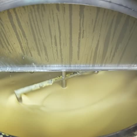 automatic mixing of milk cream inside large industrial stainless steel reservoir. large tanks for storing and fermenting dairy products. close up