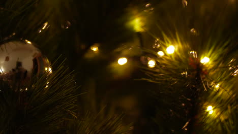 Reflexion-über-Eine-Goldene-Kugel,-Die-An-Einem-Weihnachtsbaum-Hängt,-Mit-Weihnachtsbeleuchtung-Im-Bokeh-Effekt-–-Nahaufnahme,-Schieber-Nach-Links