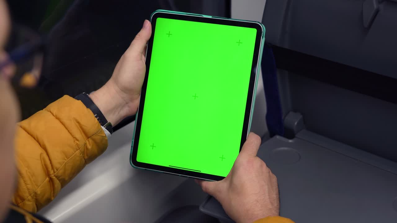 Back view of man watch tablet pc with green screen and browsing online in train. Mock up for watching content on pad. Blank digital phone in hand of guy sitting indoors in public transport. High quality 4k footage