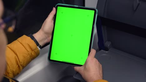 vista trasera de un hombre mirando una tableta con pantalla verde y navegando en línea en el tren. maquillaje para ver contenido en el pad. teléfono digital en blanco en la mano de un tipo sentado en el interior en el transporte público. imágenes de alta calidad 4k