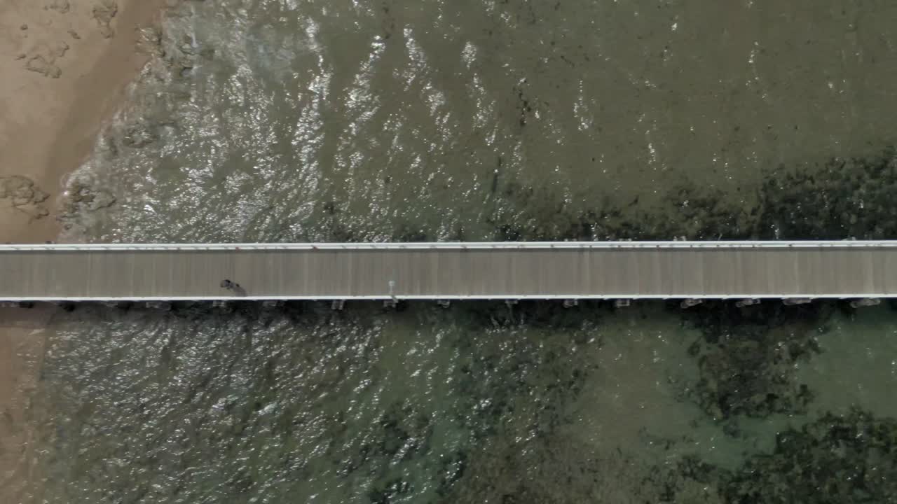 Aerial View of a Person Walking on a Pier Over the Ocean