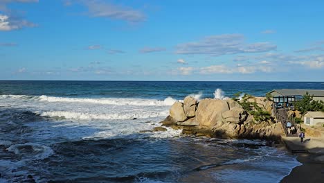 Coastal view of Yeonhwadae and waves near Hyuhyuam Hermitage, showcasing the scenic coastline and rugged rocks as visitors walk to shore