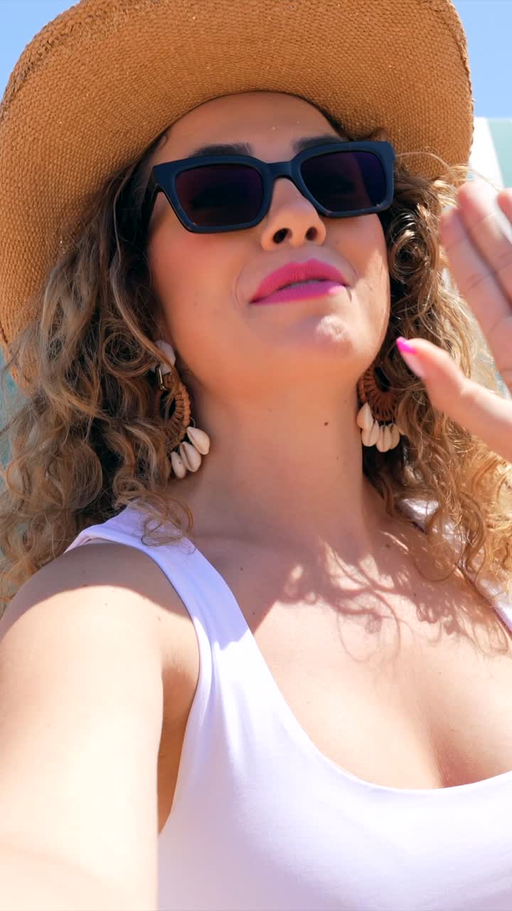 Donna con occhiali da sole e cappello sulla spiaggia