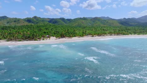 aerial trucking shot showing beautiful dominican republic island with green mountains , sandy beach and blue caribbean sea in sunlight