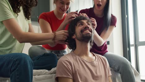 Three-women-having-fun,-creating-new-hairstyle-to-their-male-friend