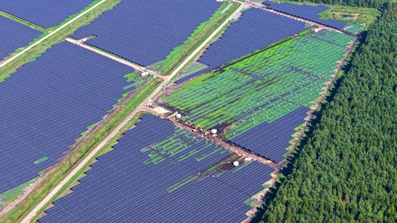 Solar panels near wind turbines in a green field, sustainability concept