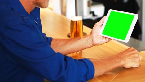 Mature-man-using-digital-tablet-while-having-beer