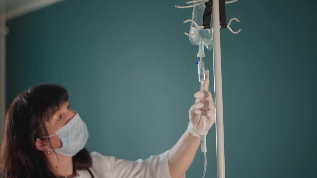 Configurazione di un dispositivo medico. Professionista sanitario gestisce con precisione la linea endovenosa. Personale medico assicura meticolosamente il corretto posizionamento e flusso del trattamento endovenoso in ambiente clinico.