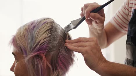 side view woman having her hair styled by a hairdresser