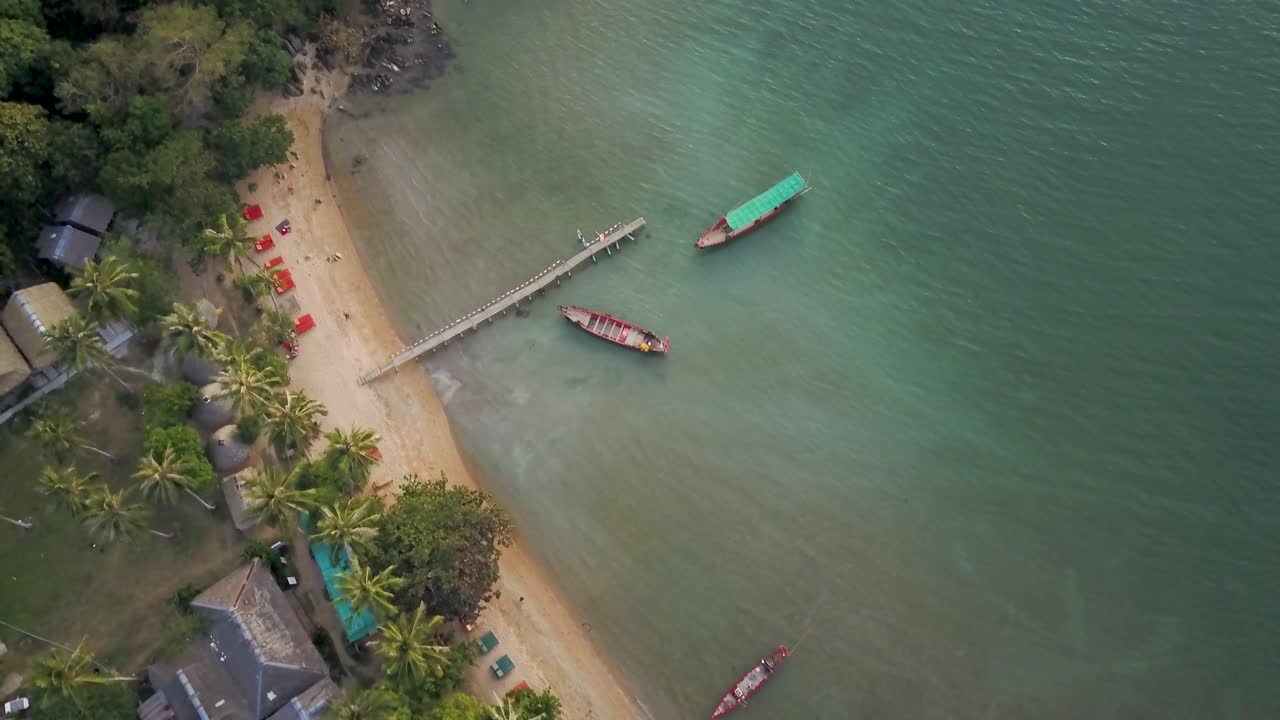 Aerial view of a tropical beach with boats and a pier