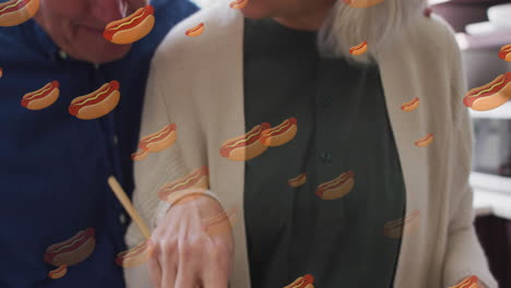 animation of hot dogs icons with senior caucasian couple cooking