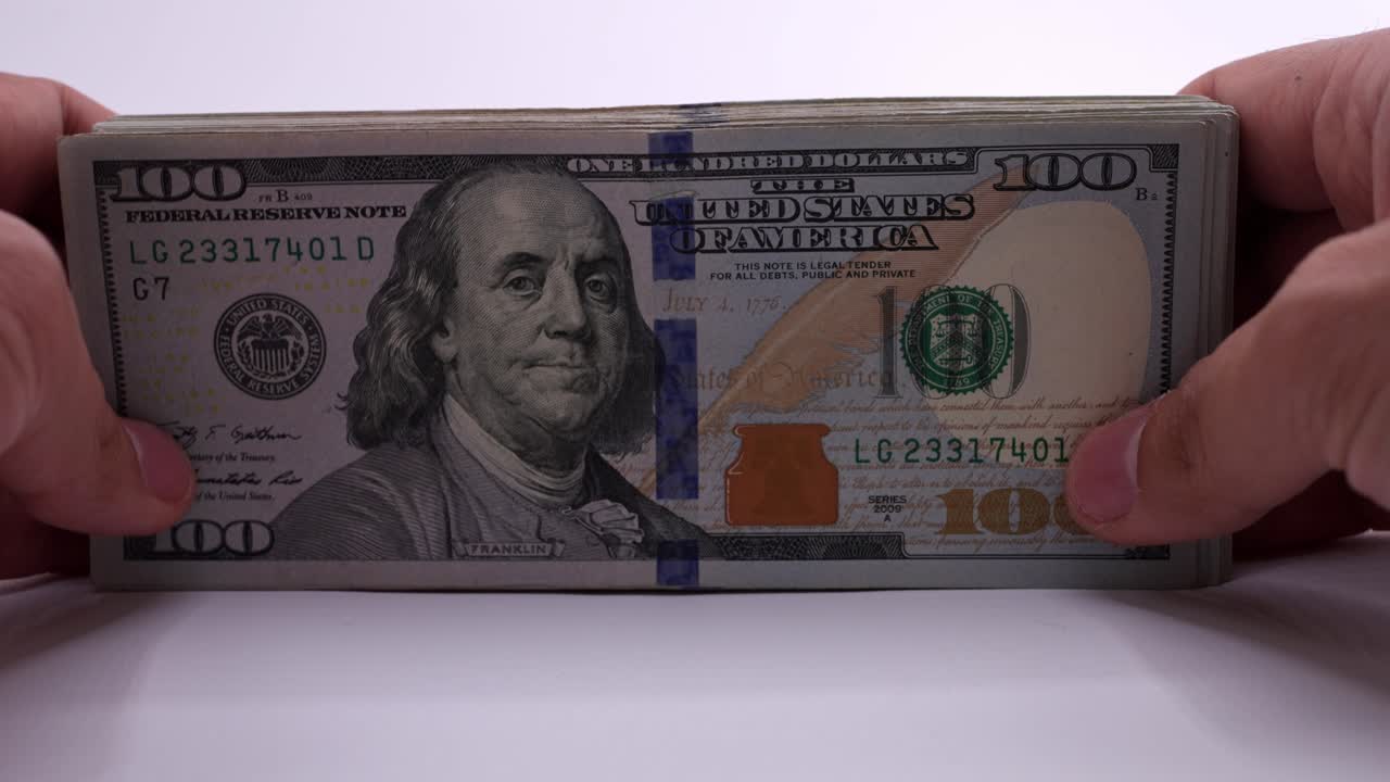 Person placing a wad of hundred-dollar bills. Slow motion close up