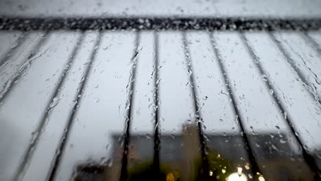 close up view looking up at window covered in rain droplets behind safety bar