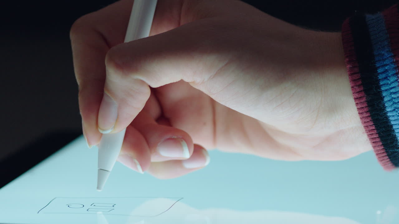 디지털 태블릿을 사용하여 스타일러스 펜으로 그림을 그리는 그래픽 디자이너가 모바일 터치 스크린 장치에서 계획 레이아웃을 스케치합니다.