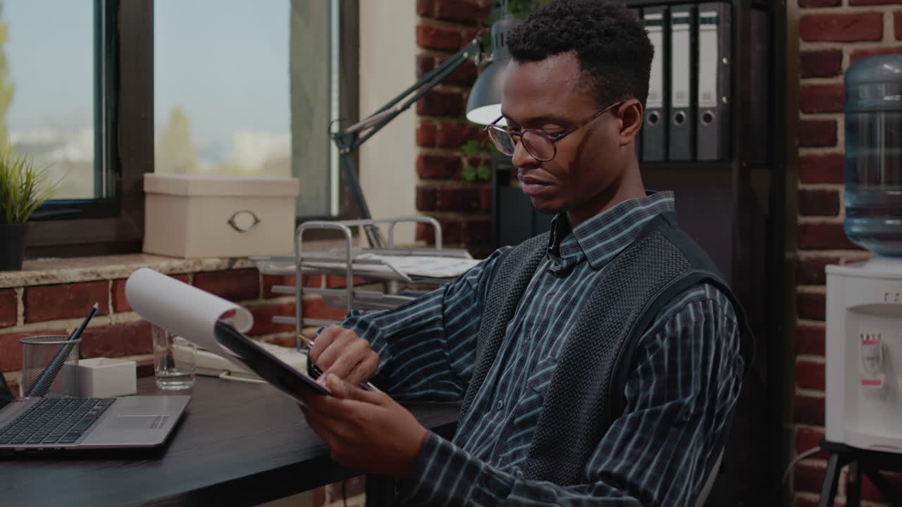 African american employee planning project with laptop and paperwork