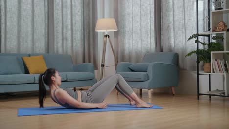 vista completa de joven entrenadora asiática mujer en ropa deportiva hablando y haciendo entrenamiento de crisscross crunch mientras enseña ejercicio en casa