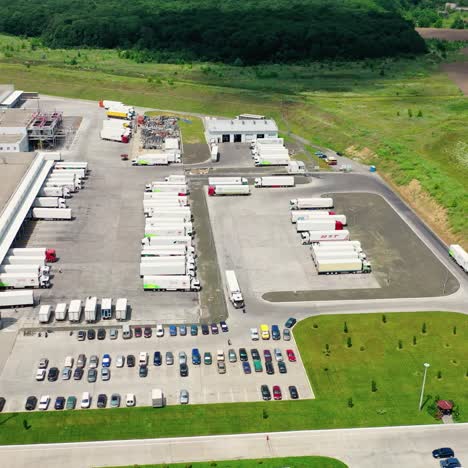 parking place with trucks and cars on field. industrial territory with car zone near beautiful green nature. aerial view