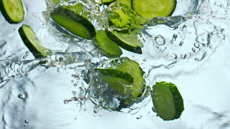 rebanadas de pepino salpicando agua en movimiento súper lento de cerca. verdura cayendo