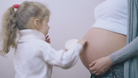 Kleines-Mädchen-Hilft-Beim-Auftragen-Von-Creme-Auf-Den-Bauch-Einer-Schwangeren-Mutter