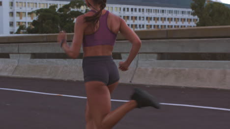 mujer corriendo en un puente de la ciudad