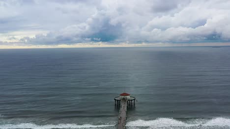 Aerial-View-Of-Manhattan-Beach-Pier-With-Roundhouse-Aquarium-In-California-On-A-Cloudy-Day---drone-shot