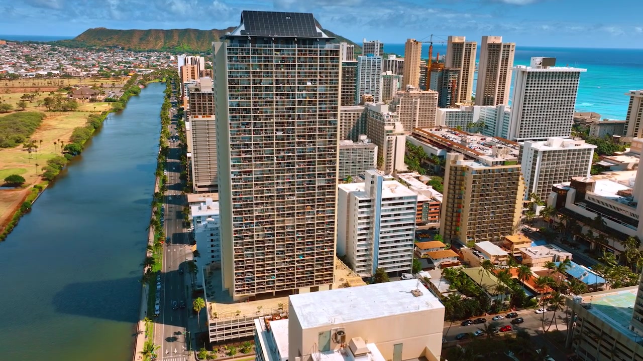 Avvicinamento a un edificio residenziale a più piani sulla riva del canale Ala Wai. Panorama di Honolulu, Hawaii, USA, da una vista aerea, con il cratere Koko Head sullo sfondo