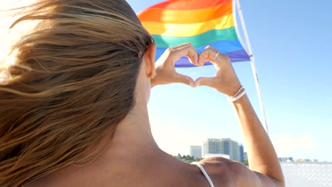 hands making heart with hands on gay rainbow flag, miami beach, lgbt concept, miami beach -slow motion