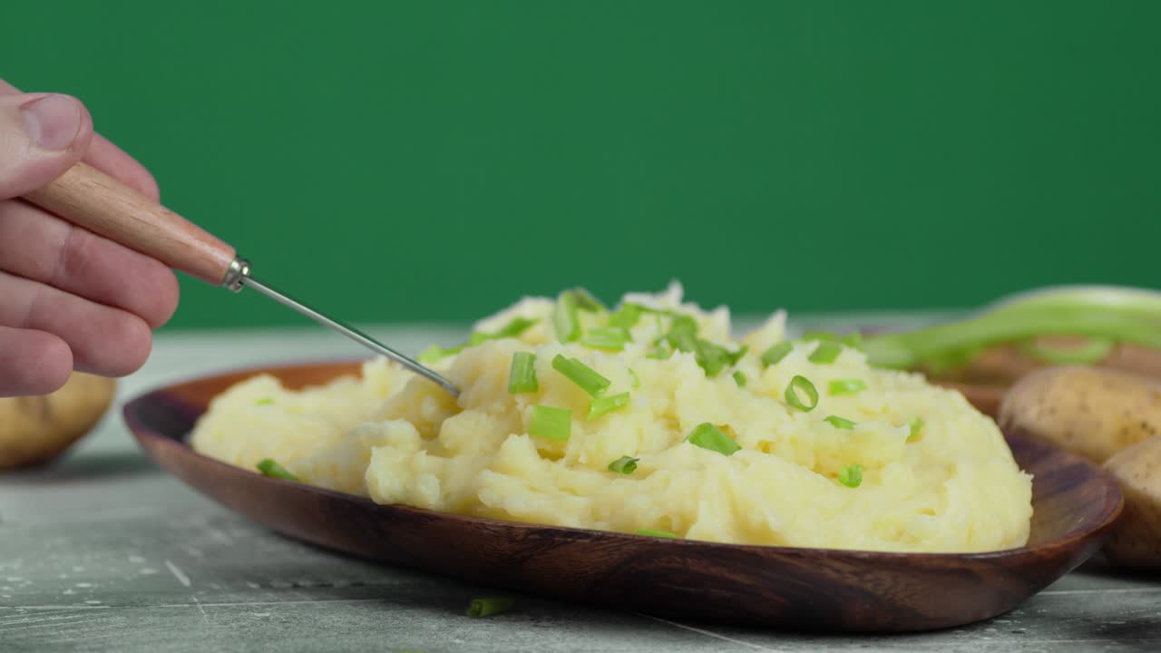 mano masculina con un tenedor mezclando puré de patatas.